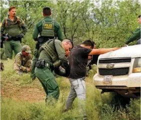  ?? AP PHOTO/MATT YORK ?? Migrants are processed Thursday after being apprehende­d by U.S. Border Patrol agents in the desert at the base of the Baboquivar­i Mountains, near Sasabe, Ariz.