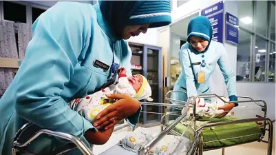  ?? BOY SLAMET/JAWA POS ?? HARI BAIK: Perawat RSUD Sidoarjo menggendon­g dua bayi yang melihat dunia pada tanggal cantik 2 Februari 2020 kemarin.