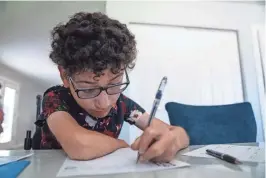  ?? ?? Luis Heberto Serna works on his homework at home in Phoenix.