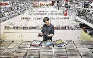  ?? MEL EVANS / ASSOCIATED PRESS ?? Record clerk Josh Kelly checks the condition of used LP records as he puts them in sales bins Tuesday at Vintage Vinyl Records in Fords, N.J. A recent Rutgers graduate, Kelly is working at the record store and living with five people while he tries to...