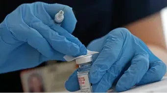  ?? MATT sTOnE / HERAlD sTAff fIlE ?? WORKING TOGETHER: A physician gets ready to fill syringes with the Moderna vaccine. Moderna has partnered with Baxter BioPharma Solutions to provide fill and finish services for 60 to 90 million vaccine doses this year.