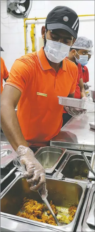  ?? (AP/Kamran Jebreili) ?? Cooks prepare free food for needy people at a restaurant in Sharjah, United Arab Emirates. In this industrial underbelly in the suburbs of Dubai, workers methodical­ly assemble packaged takeout meals of biryani rice, dal and brightly colored chicken curry for people in poverty and desperate to eat.