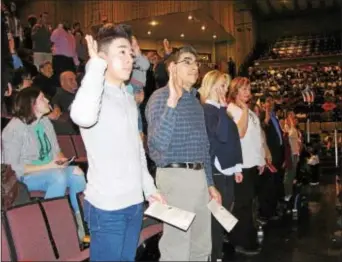  ?? KEVIN TUSTIN — DIGITAL FIRST MEDIA ?? With right hands raised, the front row of applicants took the oath of allegiance.