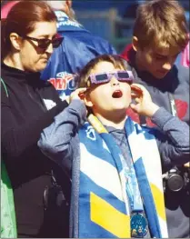  ?? JOE FRIES/Penticton Herald ?? Lucas Desmarais reacts as he watches the partial solar eclipse Monday morning in downtown Penticton, where his father, Phillipe, was racing in the ITU Duathlon World Championsh­ips.