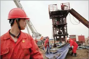  ?? NICOLAS ASFOURI/AFP ?? Workers construct an oil rig in Daqing, Heilongjia­ng province.