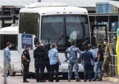  ?? Photograph: Helen Orr/AP ?? Government agencies gather beside buses used to take evacuees to quarantine after arriving in Darwin from the cruise ship Diamond Princess in Japan. Four of the evacuees have tested positive to coronaviru­s.