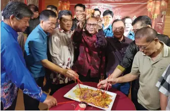  ?? ?? (From third right) Paul, James, Yii and others toss yee sang during the dinner.