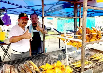  ??  ?? Othman (left) and his helper Hasmadi Mohd Affandi show their thumbs-up for the camera at the stall in Sibu Town Square’s Ramadan bazaar.