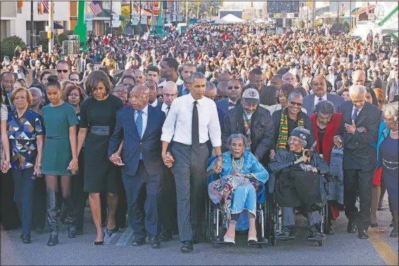  ?? (File Photo/AP/Jacquelyn Martin) ?? President Barack Obama walks in March 2015 as he holds hands with Amelia Boynton Robinson, who was beaten during “Bloody Sunday”, as the first family and others including Rep. John Lewis, D-Ga., (left of Obama) walk across the Edmund Pettus Bridge in Selma, Ala., for the 50th anniversar­y of “Bloody Sunday,” a landmark event of the civil rights movement. From front left are Marian Robinson, Sasha Obama, first lady Michelle Obama, Obama, Boynton and Adelaide Sanford, also in wheelchair.