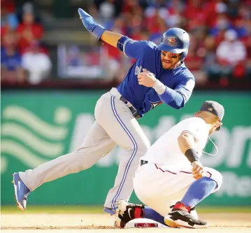  ??  ?? ARLINGTON: Toronto Blue Jays Devon Travis, left, slides safely into second ahead of the throw to Texas Rangers second baseman Rougned Odor on a passed ball during the fourth inning of Game 1 of a baseball American League Division Series in Arlington,...