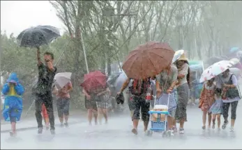  ?? WU HUANG / FOR CHINA DAILY ?? Visitors struggle through heavy rain on Friday at West Lake, a major tourist attraction in Hangzhou, capital of Zhejiang province. Typhoon Lekima is expected to make landfall by early Saturday morning in the southeast of the province.