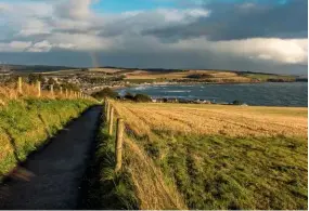  ??  ?? The path leads back through farmland to Stonehaven, with its sweeping bay stretching ahead at the bottom of the slope.