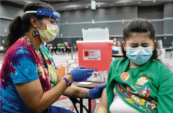  ?? Brett Coomer / Staff photograph­er ?? Registered nurse Angela Washington administer­s a COVID-19 vaccinatio­n to Linda Acosta, 10, during a vaccinatio­n clinic hosted by Texas Children’s Hospital and the city of Houston at the George R. Brown Convention Center earlier this month.