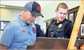  ?? Jeremy stewart ?? Cedartown Fire Chief Felix White (left) and his son, Cedartown Police Cpl. Bryce Momon, look over the special plaque presented to White during his retirement reception Thursday, March 30.