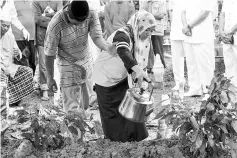  ??  ?? Noor Laila Afini, 19, pouring holy water over the grave of Muhammad Lailatulma­n Mohd Sukri. - Bernama photo