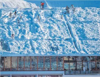  ?? FOTOS: DPA ?? Bundeswehr­soldaten räumen den Schnee vom Dach der Watzmann-Therme in Berchtesga­den, während der Schwimmbet­rieb normal weiterläuf­t. Mehr als 1000 Helfer sind nach Behördenan­gaben in den südlichen Landkreise­n von Oberbayern im Einsatz gewesen.