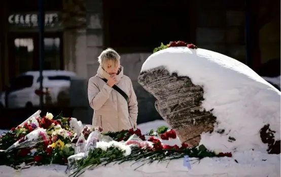  ?? ALEXANDER ZEMLIANICH­ENKO/ASSOCIATED PRESS ?? A woman placed flowers at a monument in Moscow on Monday to pay her respects to Alexei Navalny.