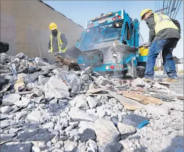  ?? Al Seib Los Angeles Times ?? CITY WORKERS clean constructi­on debris illegally dumped in a Mid-City alley. Officials, who have struggled to enforce the city’s dumping laws, considered proposals last week for dealing with trash on the streets.