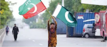 ?? File /Associated Press ?? ↑ A young supporter of PTI holds flags near Imran Khan’s house in Lahore.