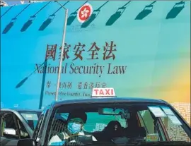  ?? Vincent Yu Associated Press ?? PASSAGE of the law by China’s top legislatur­e plunges Beijing’s relationsh­ip with major powers into uncertaint­y. Above, a taxi drives past a banner touting the law.