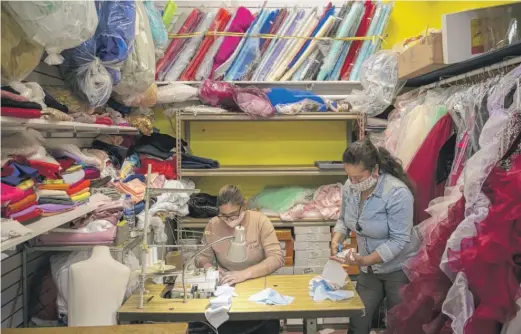  ?? ASHLEE REZIN GARCIA/SUN-TIMES PHOTOS ?? Tania Hernandez (left) and Florina Saldana, dressmaker­s at Novias Davila, in Little Village, make masks last week.