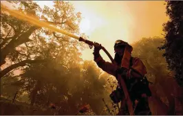  ?? RICH PEDRONCELL­I / AP ?? Firefighte­r Jason Sheumann sprays a home as he battles a wildfire Monday in Napa, Calif. Wildfires in wine country destroyed at least 1,500 homes and businesses. Thousands of people fled as flames raged unchecked throughout the region.