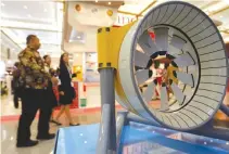  ??  ?? PEOPLE WALK past a model of marine turbine for generating electricit­y from underwater tidal streams, at an infrastruc­ture expo in Jakarta, Indonesia on Nov. 11.