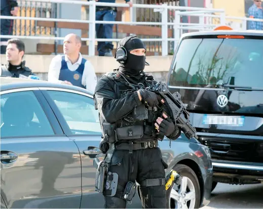  ??  ?? Un policier de l’équipe tactique monte la garde devant le collège Alexis de Tocquevill­e où s’est produit le drame.