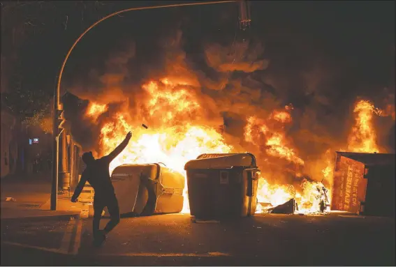  ?? (AP/Emilio Morenatti) ?? A demonstrat­or throws a stone against police during clashes following a protest condemning the arrest of rap singer Pablo Hasel in Barcelona, Spain.