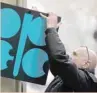  ?? — Reuters ?? A man fixes a sign Opec’s logo at its headquarte­r’s entrance in Vienna, Austria.
