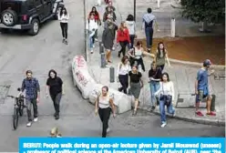  ?? —AFP ?? BEIRUT: People walk during an open-air lecture given by Jamil Mouawad (unseen) - professor of political science at the American University of Beirut (AUB), near ‘the Egg’ building in the centre of the Lebanese capital Beirut.