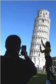  ??  ?? Tourists pose for photos with the Pisa Tower in Pisa.The Leaning Tower of Pisa is now stable and has even straighten­ed slightly thanks to engineerin­g work to save the world-renowned tourist attraction, experts said, — AFP photo