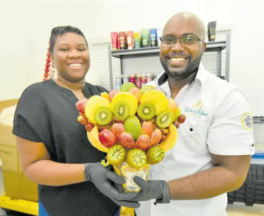  ?? IAN ALLEN/PHOTOGRAPH­ER ?? Brittney (left) and Paul Romelus pose with a recently created edible arrangemen­t.