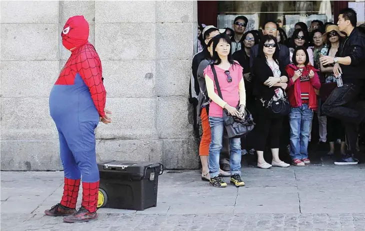  ?? —AP ?? MADRID: A man wearing a Spiderman outfit performs for money as tourists look at the main square. Spanish savers vented their fury against bailed-out Bankia yesterday after the alreadydim­inished value of their stock investment­s in the bank plummeted by...