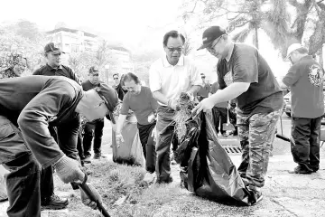  ??  ?? Wong (fourth from right) and Hii (third right) leading volunteers in the clean-up at Singapore Road, yesterday.