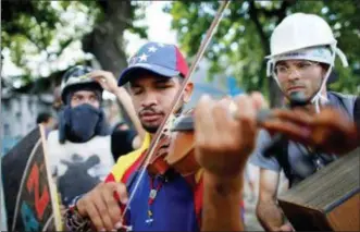  ?? ARIANA CUBILLOS — THE ASSOCIATED PRESS FILE ?? In this file photo, Wuilly Arteaga plays his violin during clashes against Venezuelan Bolivarian National Guard officers on the first day of a 48-hour general strike in protest of government plans to rewrite the constituti­on, in the Bello Campo...