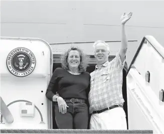  ?? Associated Press ?? Christophe­r Jenkins waves while he stands with Julia Mord on Sept. 18 as they mimic a presidenti­al arrival for a friend who is taking their picture during their tour of the Air Force One Experience, a full-sized 747 replica of Air Force One that is now...