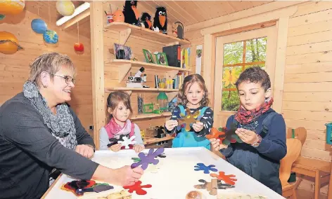  ?? FOTO: UWE MISERIUS ?? Am kommenden Dienstag ist Eröffnung. Kita-Leiterin Cornelia Hahn testete die Öko-Laube gestern schon einmal mit Lennya, Alina und Gabriel.