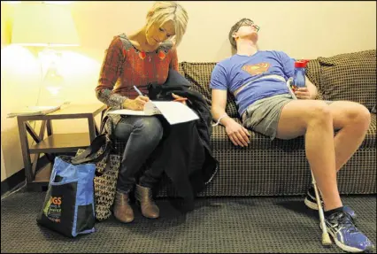  ??  ?? Exhausted from a morning of therapy, Clark falls asleep while his mom, Mariellen Jacobs, fills out forms for him in a waiting room at the Shepherd Center.