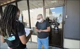  ?? GERALD HERBERT/AP ?? Dazmine Allen, left, gives store owner Kenneth McGruder some virus info in New Orleans.