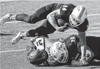  ?? STAFF PHOTO BY DOUG STRICKLAND ?? UTC running back Derrick Craine goes over teammate Jacob Revis, right, and Samford linebacker Aaron Harris during Saturday’s game at Finley Stadium. Craine finished with a career-high 222 rushing yards and helped the Mocs win the Southern Conference...