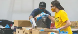  ?? BRANDON HARDER ?? Keenan Cummings, left, and Laura Anaka place food items into hampers at Archbishop M.C. O’neill Catholic High School in Regina.