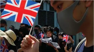  ?? Associated Press ?? A group of Hong Kong residents wave U.K. flags on Oct. 1, 2019, requesting the right to British residency outside the British embassy in Hong Kong. Hong Kong’s government says it will ban all passenger flights from the U.K., starting Thursday, to curb the spread of new variants of the coronaviru­s.