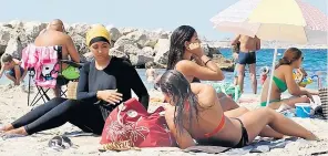  ??  ?? A woman wears a burkini on a beach in France, where the garment had been banned