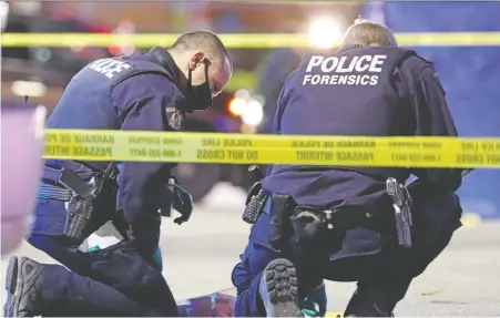  ?? Shane MACKichan ?? Police investigat­e the scene after a man was shot and killed Sunday night outside a Shoppers Drug Mart in Surrey.