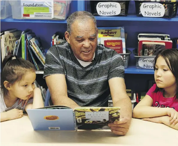  ?? IAN KUCERAK ?? Hugh Derrick, 72, a retired bus driver, reads the Magpie Song book to Chloe, left, 6, and Adriana, 9, at Prince Charles School in Edmonton. Derrick takes two children at a time to the library and reads stories, leads them in word games and asks them to...