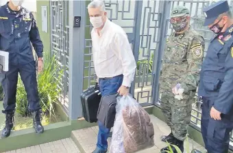  ??  ?? El intendente José Carlos Acevedo sale de su casa acompañado por policías y un militar. Luego abordó una ambulancia y fue llevado al destacamen­to militar R.I. 10 Sauce del distrito de Concepción.