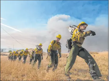  ?? ?? Firefighte­rs walk in a line during a wildfire in Castaic, Calif., on Wednesday.