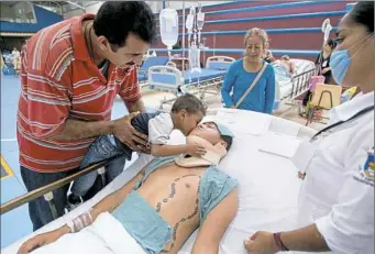  ?? Rebecca Blackwell/Associated Press ?? Three-year-old Uziel kisses his father, Ivan Dominguez Diaz, 27, who awaits surgery for a broken neck Saturday at a ward set up on a school basketball court in Juchitan, Mexico.