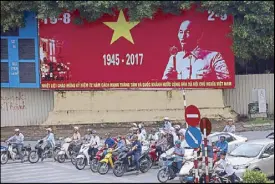  ??  ?? People drive past a poster of the late former president Ho Chi Minh marking the 72nd anniversar­y of National Day in Hanoi, Vietnam yesterday. EPA